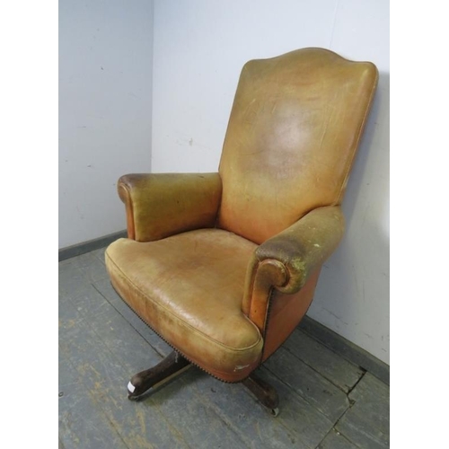 718 - A vintage high-backed revolving desk chair, upholstered in distressed tan leather with brass studs, ... 