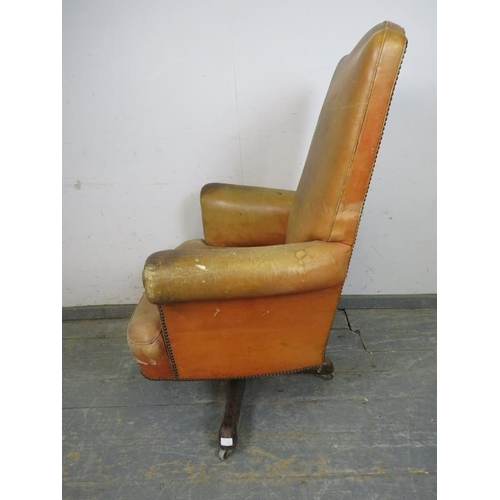 718 - A vintage high-backed revolving desk chair, upholstered in distressed tan leather with brass studs, ... 