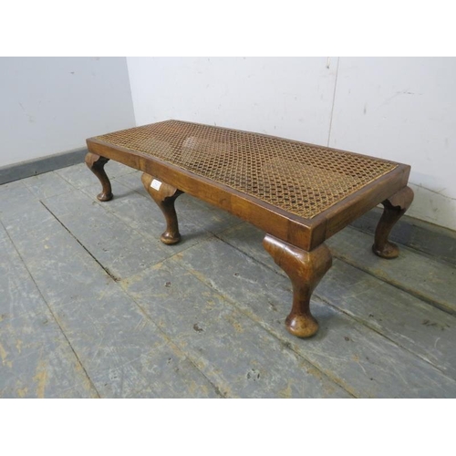 770 - A 1920s walnut long footstool, the bergere top with loose squab cushion recovered in buttoned pale-y... 