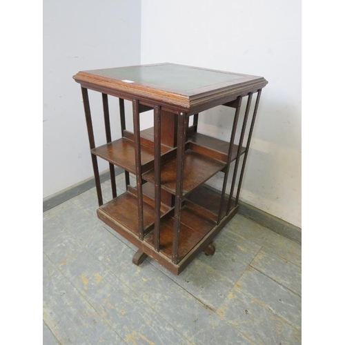 799 - An early 20th century oak revolving bookcase, the top with inset gilt tooled green leather, above ei... 