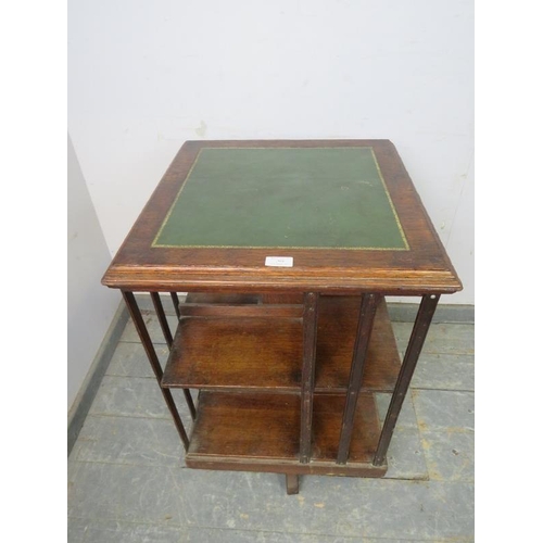 799 - An early 20th century oak revolving bookcase, the top with inset gilt tooled green leather, above ei... 