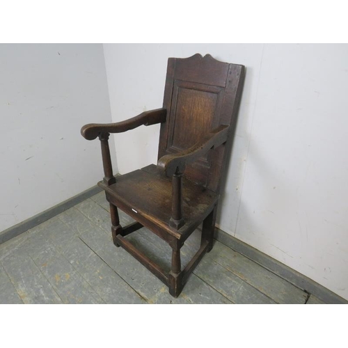 803 - An 18th century oak wainscot chair, the panelled back joined with shaped arms to a planked seat, on ... 