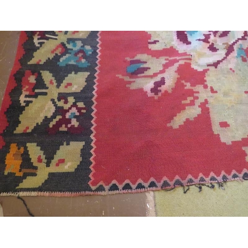 864 - Mid 20th Century Persian Kilim carpet with large floral images on a red ground and deep end borders.... 