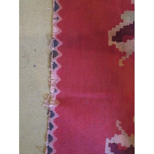 864 - Mid 20th Century Persian Kilim carpet with large floral images on a red ground and deep end borders.... 