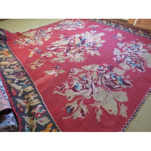 864 - Mid 20th Century Persian Kilim carpet with large floral images on a red ground and deep end borders.... 