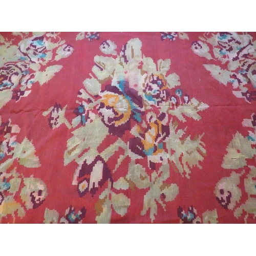 864 - Mid 20th Century Persian Kilim carpet with large floral images on a red ground and deep end borders.... 