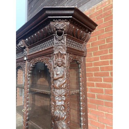 720 - A 19th century oak glazed display cabinet, profusely carved in the 17th century taste with caryatids... 