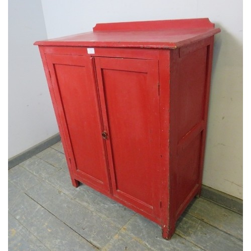 753 - A 19th century pine side cabinet painted red, the panelled doors opening onto two loose shelves, on ... 