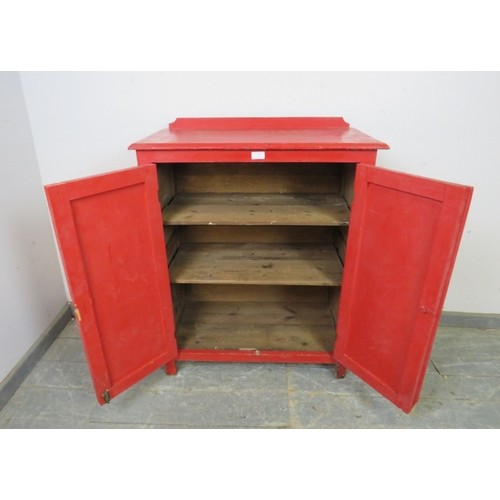 753 - A 19th century pine side cabinet painted red, the panelled doors opening onto two loose shelves, on ... 