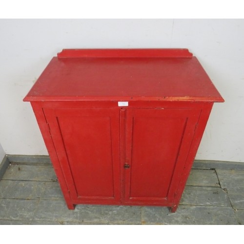 753 - A 19th century pine side cabinet painted red, the panelled doors opening onto two loose shelves, on ... 