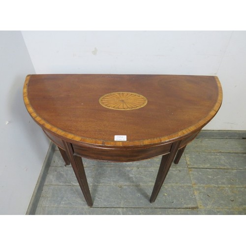 730A - A George III mahogany demi-lune folding card table, crossbanded and with inlaid satinwood panel, hou... 