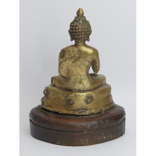 211 - A Nepalese brass Buddha, 20th century. Depicted seated on a double lotus base and mounted on a carve... 