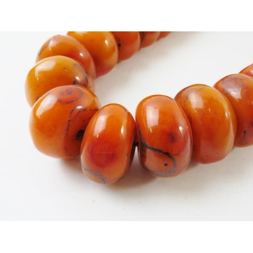 430 - A strand of Moroccan berber large ‘pressed amber/resin beads’ approximate 30mm average diameter, 340... 