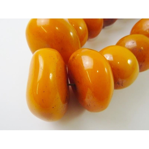 431 - A graduated string of Moroccan berber ‘pressed amber/resin’ beads,  the largest 6.2mm wide, 650gms a... 