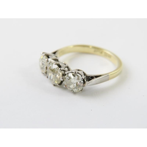 443 - A three stone diamond ring, the old cut diamonds claw set in white to a yellow metal shank.  The dia... 