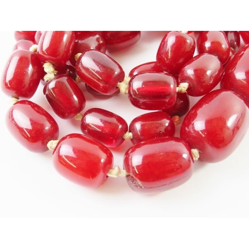 448 - A graduated strand of red ‘cherry amber’ beads, the largest 26mm x 20mm. 96.5 gms approx