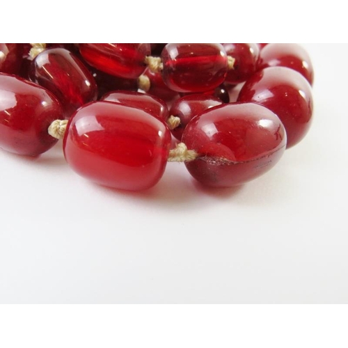 448 - A graduated strand of red ‘cherry amber’ beads, the largest 26mm x 20mm. 96.5 gms approx