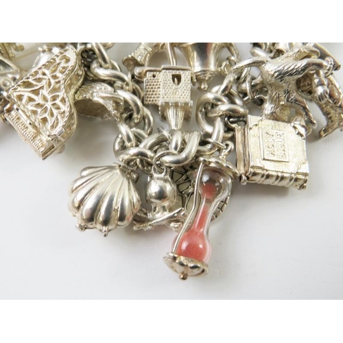 458 - A silver curb link charm bracelet set with 22 assorted white metal charms, with padlock clasp hallma... 