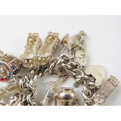 458 - A silver curb link charm bracelet set with 22 assorted white metal charms, with padlock clasp hallma... 