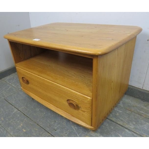 730 - A vintage elm Windsor media unit by Ercol, with triangular drop-leaf, housing an open shelf above on... 