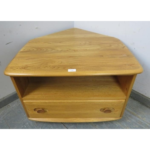 730 - A vintage elm Windsor media unit by Ercol, with triangular drop-leaf, housing an open shelf above on... 