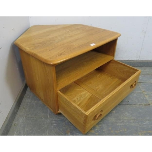 730 - A vintage elm Windsor media unit by Ercol, with triangular drop-leaf, housing an open shelf above on... 