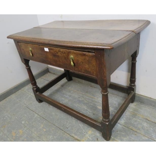 747 - An 18th century oak side table, housing one long with brass drop handles, on turned and block suppor... 