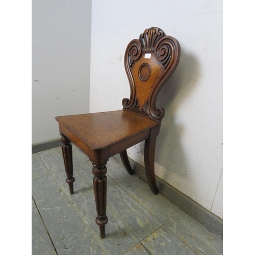 759 - A Victorian medium oak hall chair, the shaped backrest with relief carved scroll decoration, on flut... 