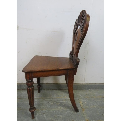 759 - A Victorian medium oak hall chair, the shaped backrest with relief carved scroll decoration, on flut... 