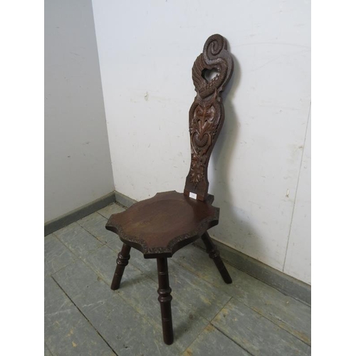 760 - A vintage oak Welsh spinning stool, the backrest ornately carved with a serpent, thistles and heart ... 