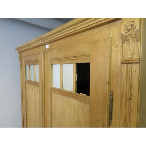 796 - An antique pine Continental double wardrobe, the twin doors with inset antiqued mirror panels, above... 