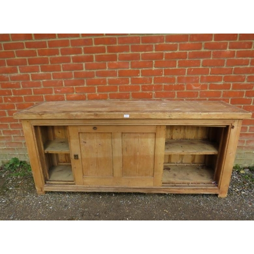 813 - An antique pine kitchen sideboard/dresser base, the sliding doors with recessed brass handles, openi... 