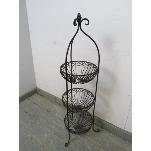 816 - An antique style wrought iron three-tier vegetable/fruit stand, the scrolled cornice with asparagus ... 