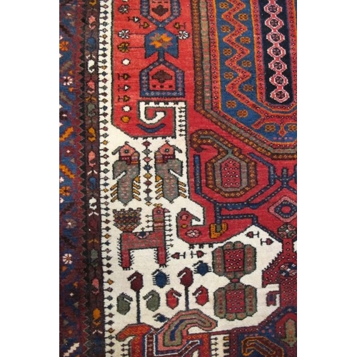 858 - A 20th Century Persian rug, central motif on red ground with styalised animals. 220cm x 142cm approx... 