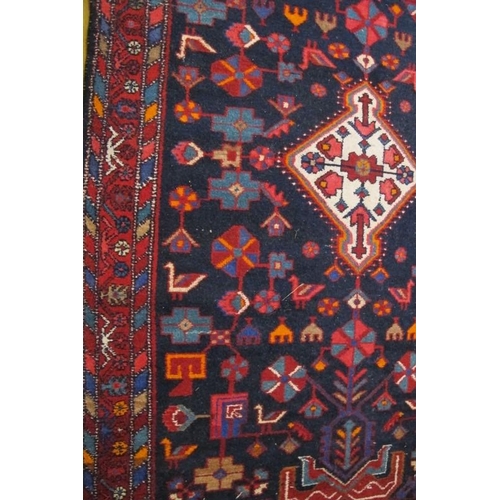 859 - A 20th Century Persian rug with a small central motif in cream, surrounded by a block pattern of sty... 