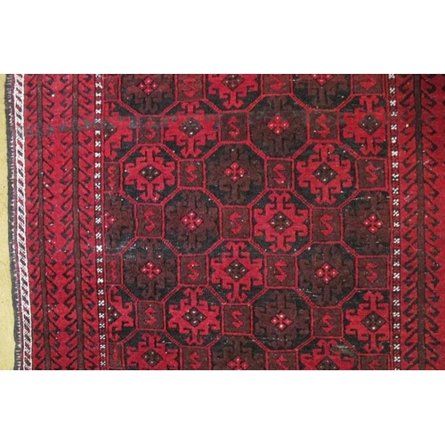 861 - A 20th Century Persian Baluch rug, repeat pattern on red ground. 200cm x 98cm approx.
Condition repo... 