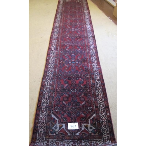 863 - A 20th Century Persian runner, central pattern on red ground with cream border. 389cm x 81cm approx.... 