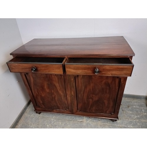 750A - A Regency Period flame mahogany linen cupboard, the top with reeded edge, housing two short drawers ... 