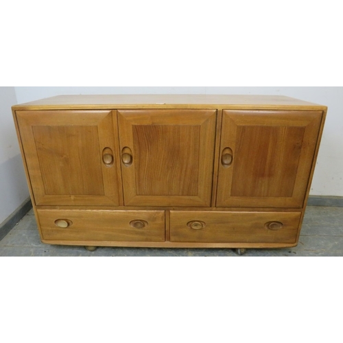 747 - An Ercol sideboard with three cupboard doors over two long drawers, each with dished wooden handles ... 