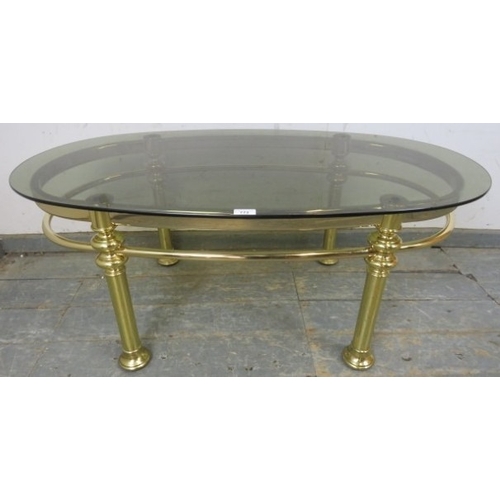 772A - A 1980s Retro brass tubular coffee table with oval smoked glass top.
H45cm x W111cm x D61cm (approx)... 