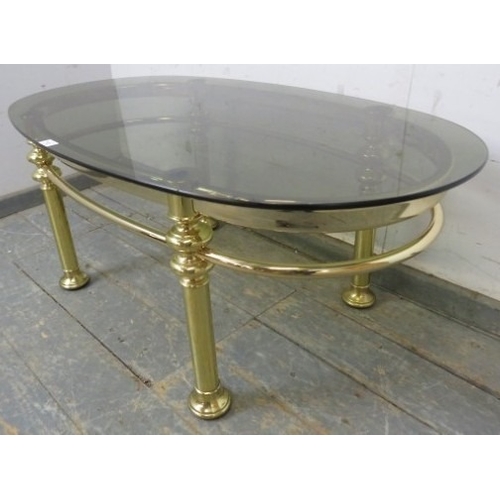 772A - A 1980s Retro brass tubular coffee table with oval smoked glass top.
H45cm x W111cm x D61cm (approx)... 