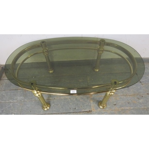 772A - A 1980s Retro brass tubular coffee table with oval smoked glass top.
H45cm x W111cm x D61cm (approx)... 