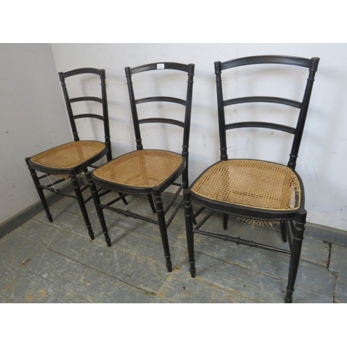 783 - A set of three 20th century ebonised ladderback dining chairs with rattan seats raised on turned and... 