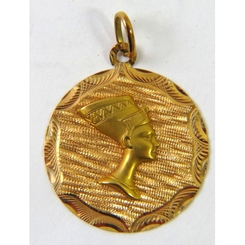 475 - An Egyptian round pendant depicting Nefertiti’s head in profile, 30mm diameter, stamped 750 with Egy... 
