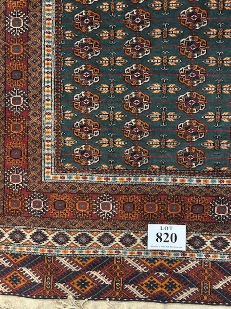 A Persian Bokara rug with a central repeat pattern field and wide ...