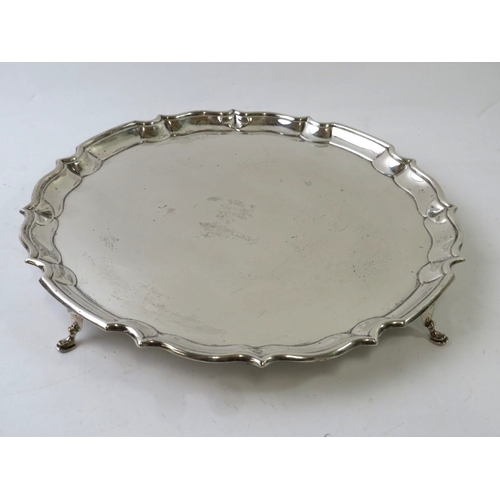 An Edwardian silver salver with pie crust rim and standing on four pad ...