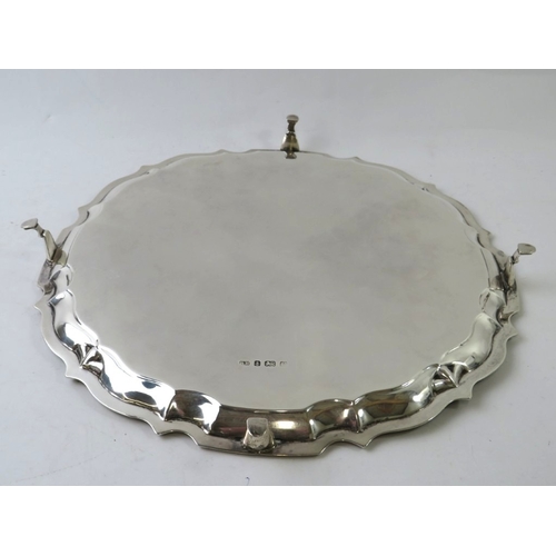 An Edwardian silver salver with pie crust rim and standing on four pad ...