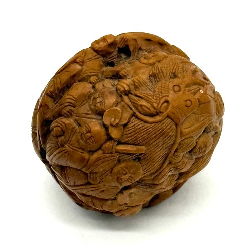 A 19th century Chinese carved walnut shell decorated with various figures