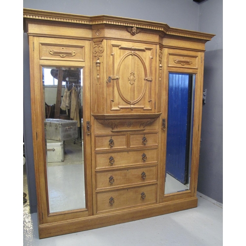 88 - LATE VICTORIAN OAK BREAK FRONT WARDROBE having moulded and dentil cornice with moulded cherub face a... 