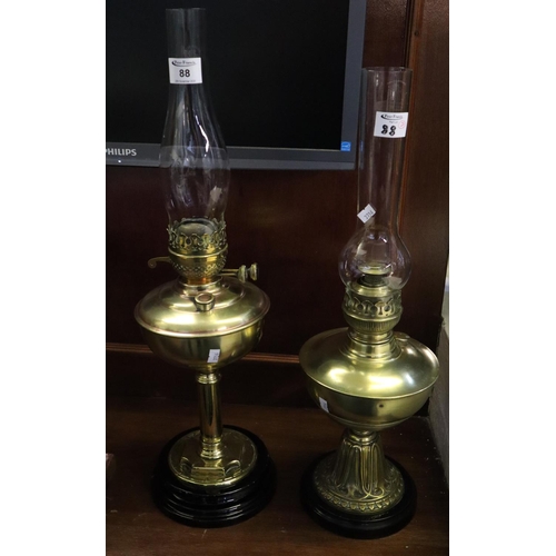 88 - Two similar brass oil lamps with brass reservoirs and brass pedestals on ceramic bases with clear ch... 